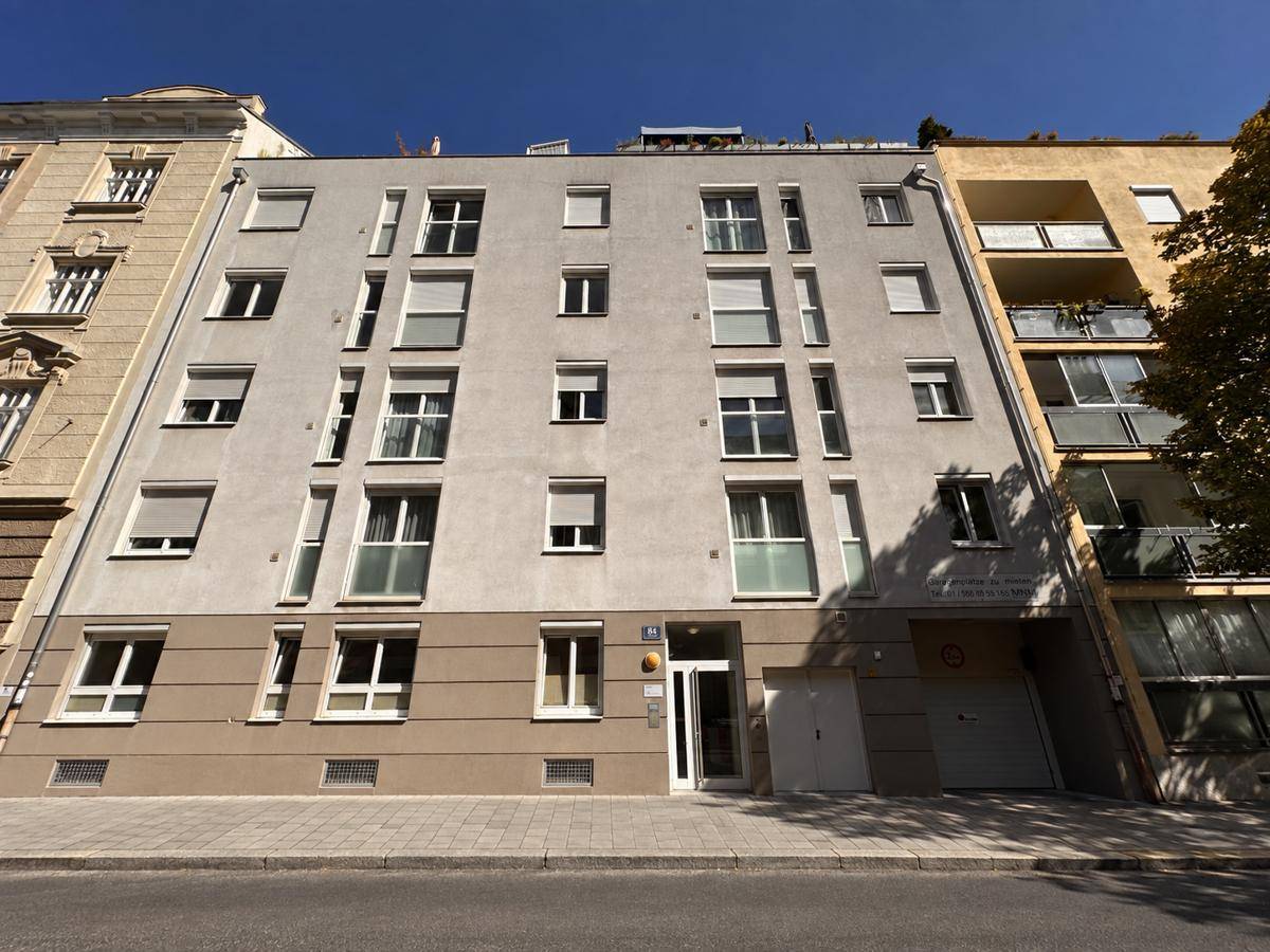 Moderne Wohnhausfassade mit vielen Fenstern und Balkonen in städtischer Umgebung.