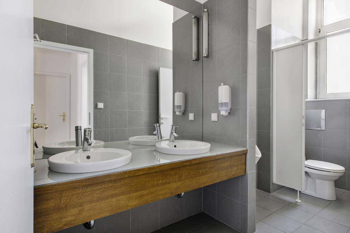 Modernes Badezimmer mit grauen Fliesen, Doppelwaschbecken und einem Urinal.