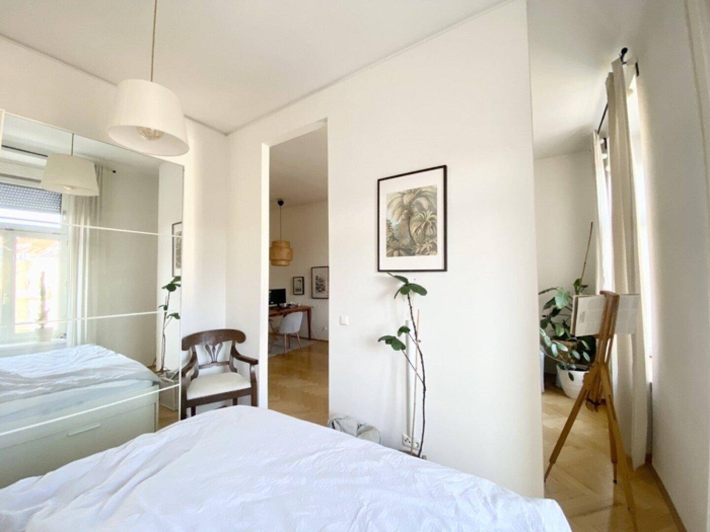 Schlafzimmer mit Spiegelschrank und Blick in den angrenzenden Wohnbereich, hell und offen gestaltet.