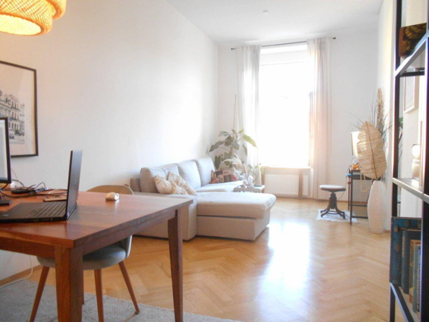 Geräumiger Wohnbereich mit Esstisch, Sofa und viel Tageslicht, ideal für Arbeit und Entspannung.