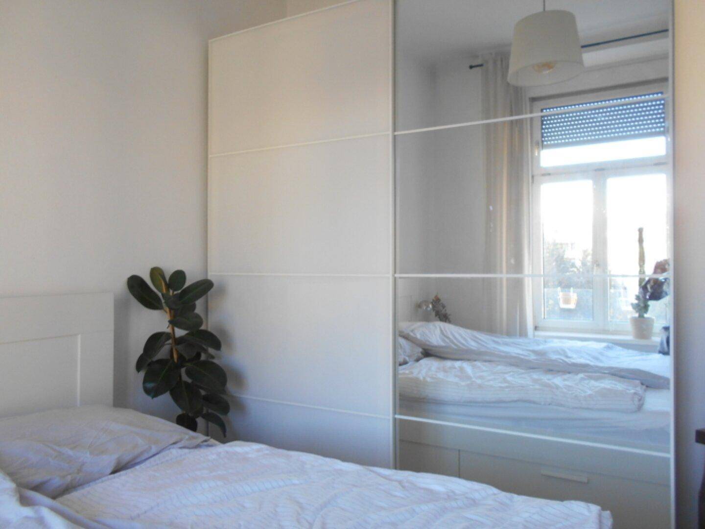 Helles Schlafzimmer mit großem Bett und praktischem Spiegelschrank, der den Raum optisch erweitert.