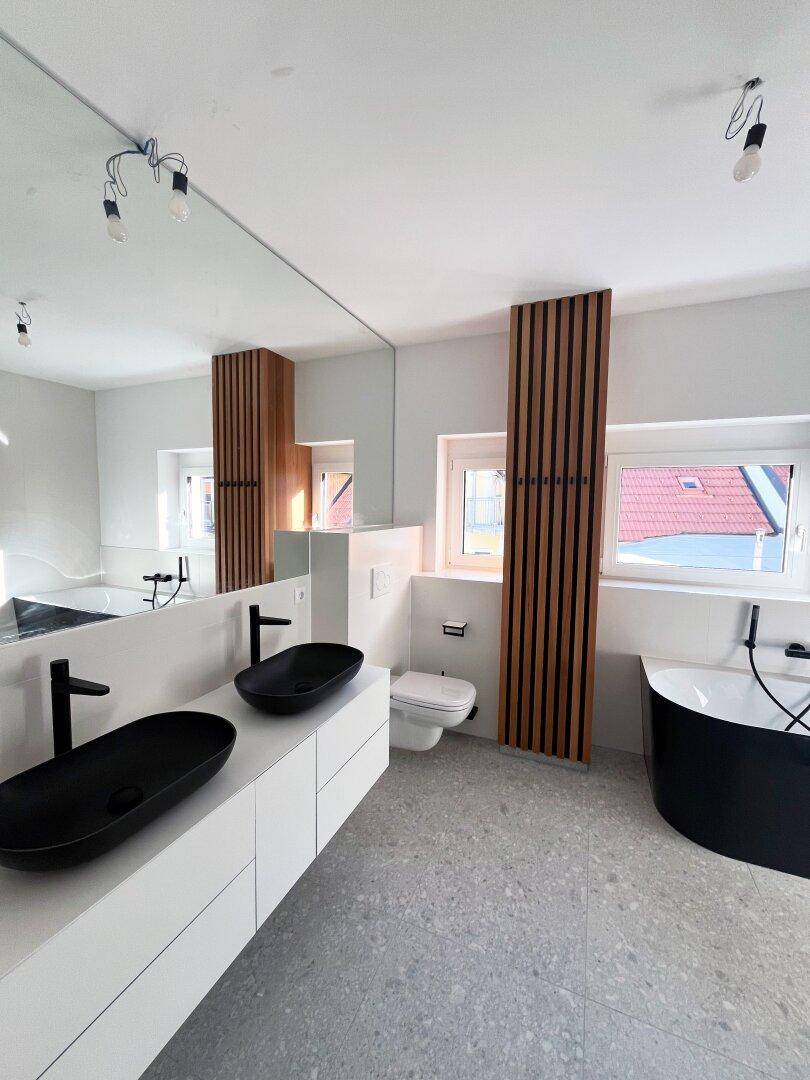 Stilvolles Badezimmer mit Doppelwaschbecken, freistehender Badewanne und modernen Armaturen.