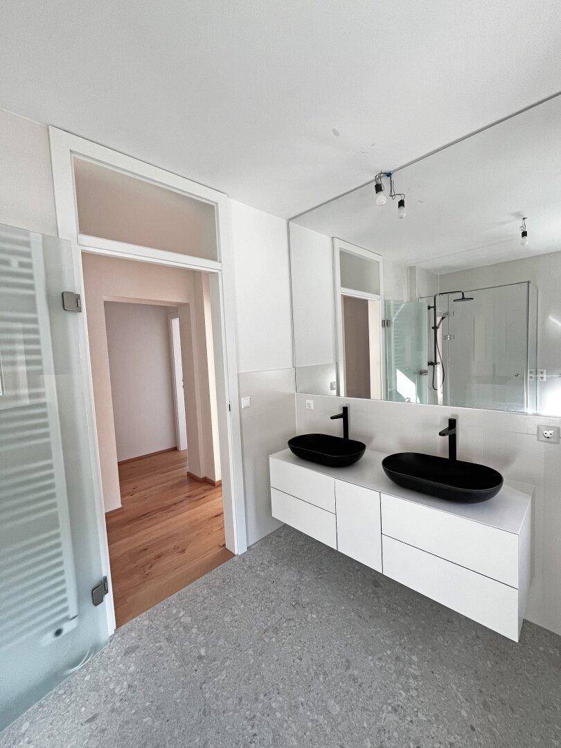 Modernes Badezimmer mit Doppelwaschbecken, großer Spiegelfläche und begehbarer Dusche.