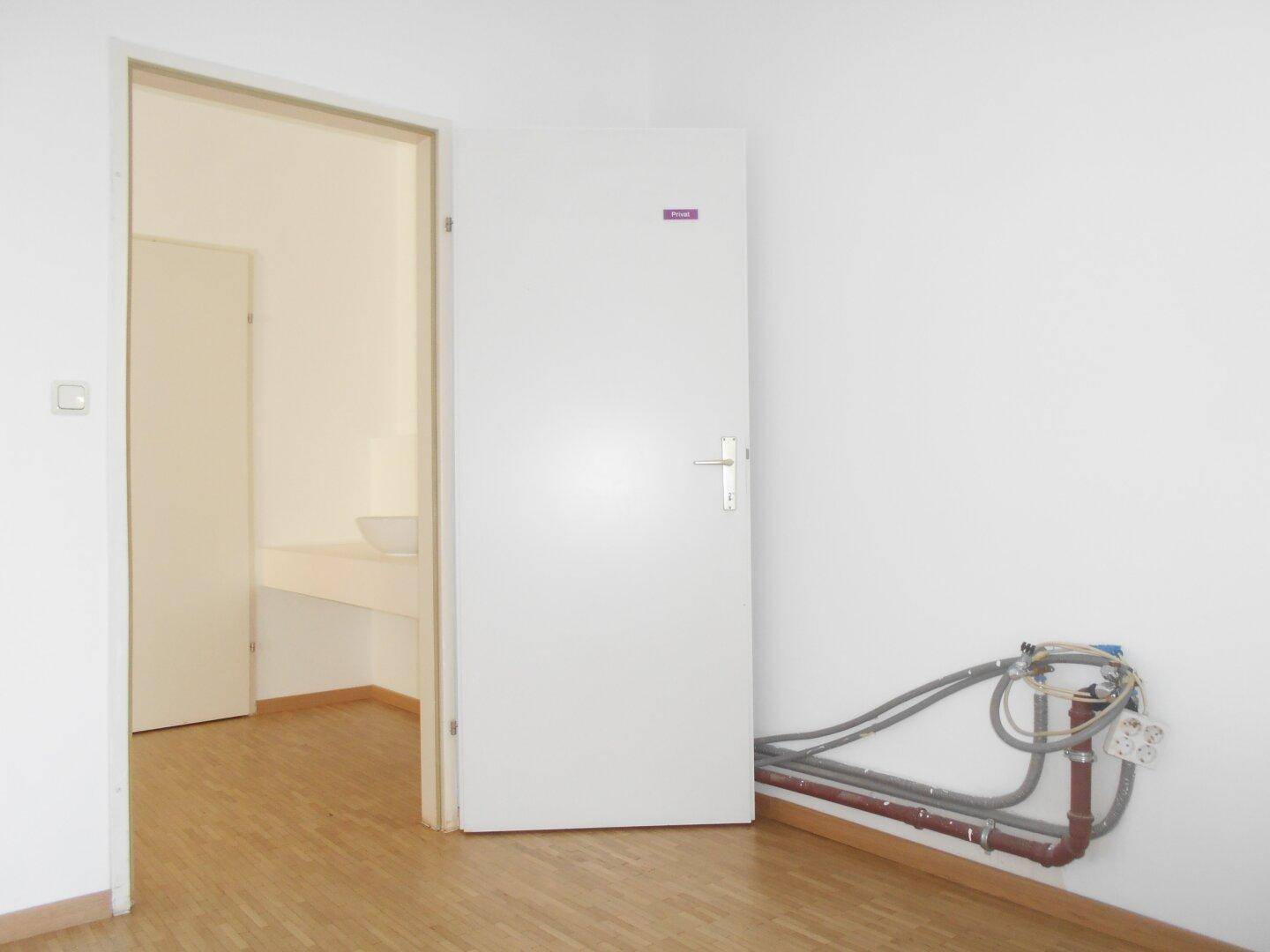 Raum mit sichtbaren Wasseranschlüssen und Abflüssen, bereit für die Installation einer Küche oder eines Sanitärbereichs.