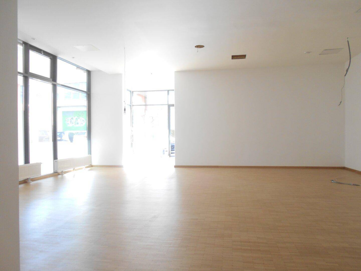 Weitläufiger, heller Gewerberaum mit großen Fensterfronten, die den Raum mit Sonnenlicht durchfluten.