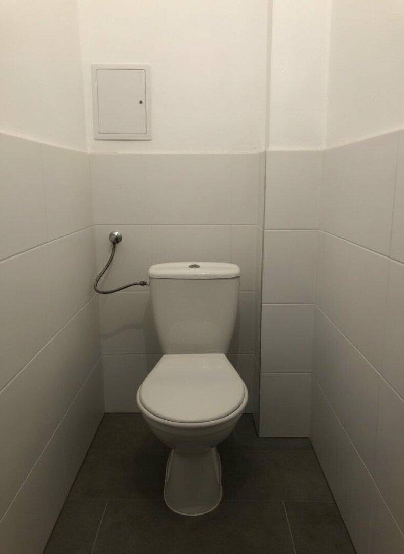 Separates WC mit Toilette und weißen Wandfliesen, funktional und sauber gestaltet.