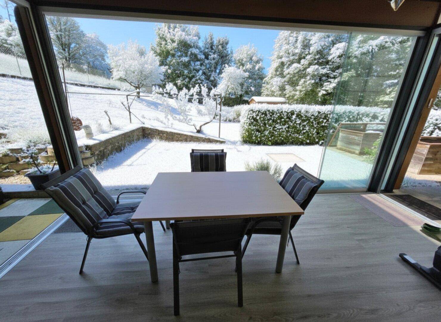 Gebäudeansicht im Winter mit schneebedeckten Balkonen und einem verglasten Wintergarten im Erdgeschoss.