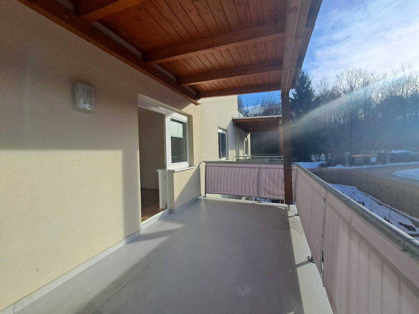 Überdachter Balkon mit Holzbalken und Ausblick auf die winterliche Umgebung.