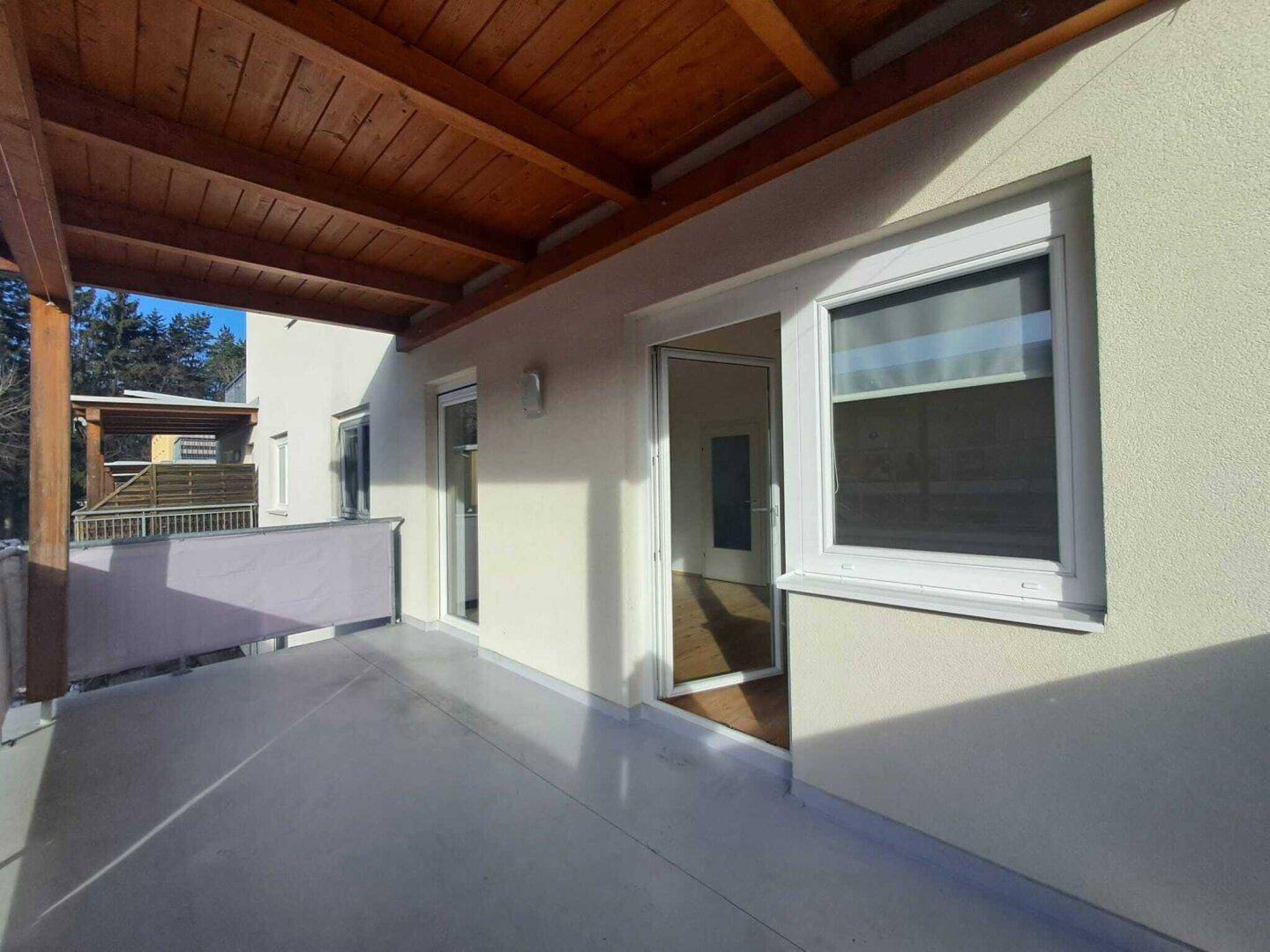 Geräumiger Balkon mit Holzdach und Blick auf die verschneite Landschaft.