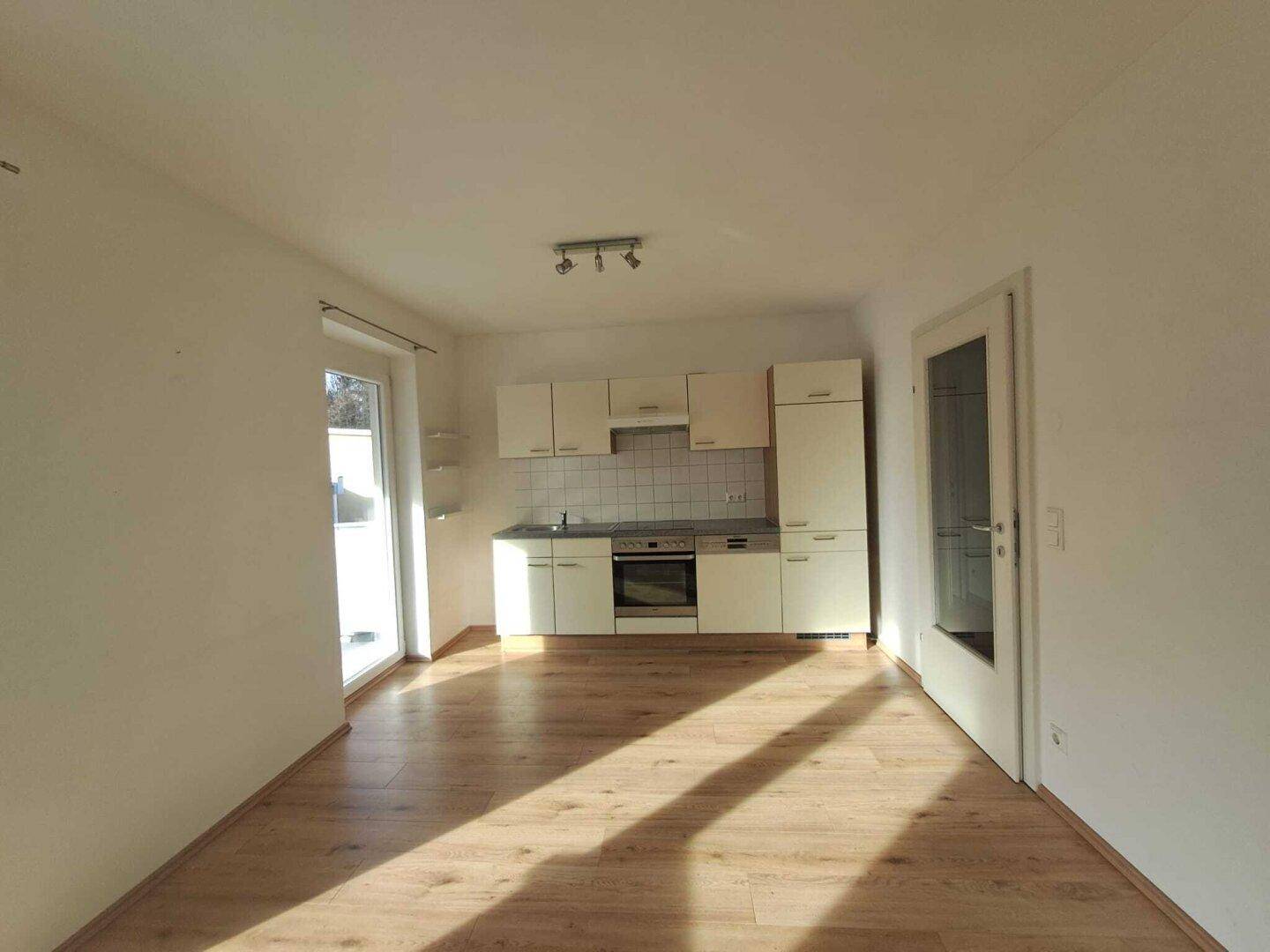 Lichtdurchflutete Küche mit Einbaugeräten und hellem Holzfußboden.