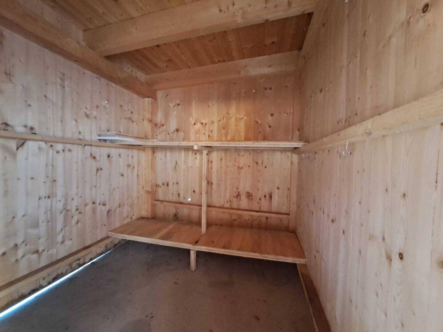 Innenraum eines Holzschuppens mit Regalen für Lagerzwecke.