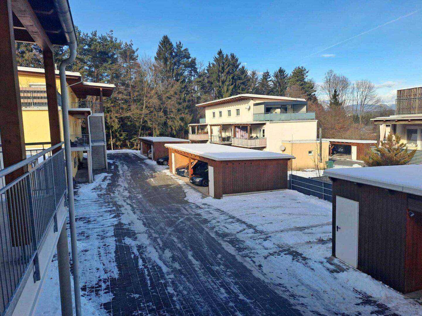 Wohnanlage mit mehreren Gebäuden und Carports in verschneiter Landschaft.