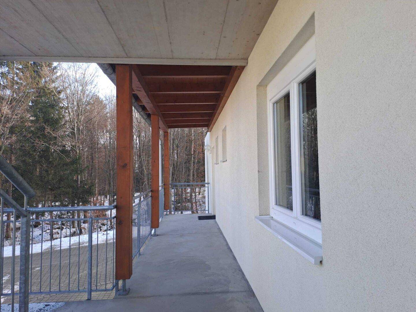 Überdachter Außenbereich mit Holzsäulen und Blick ins Grüne.