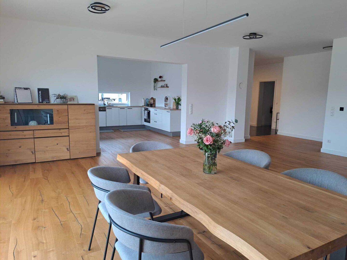 Geräumiger Essbereich mit Holzboden und offener Verbindung zur modernen Küche im Hintergrund.