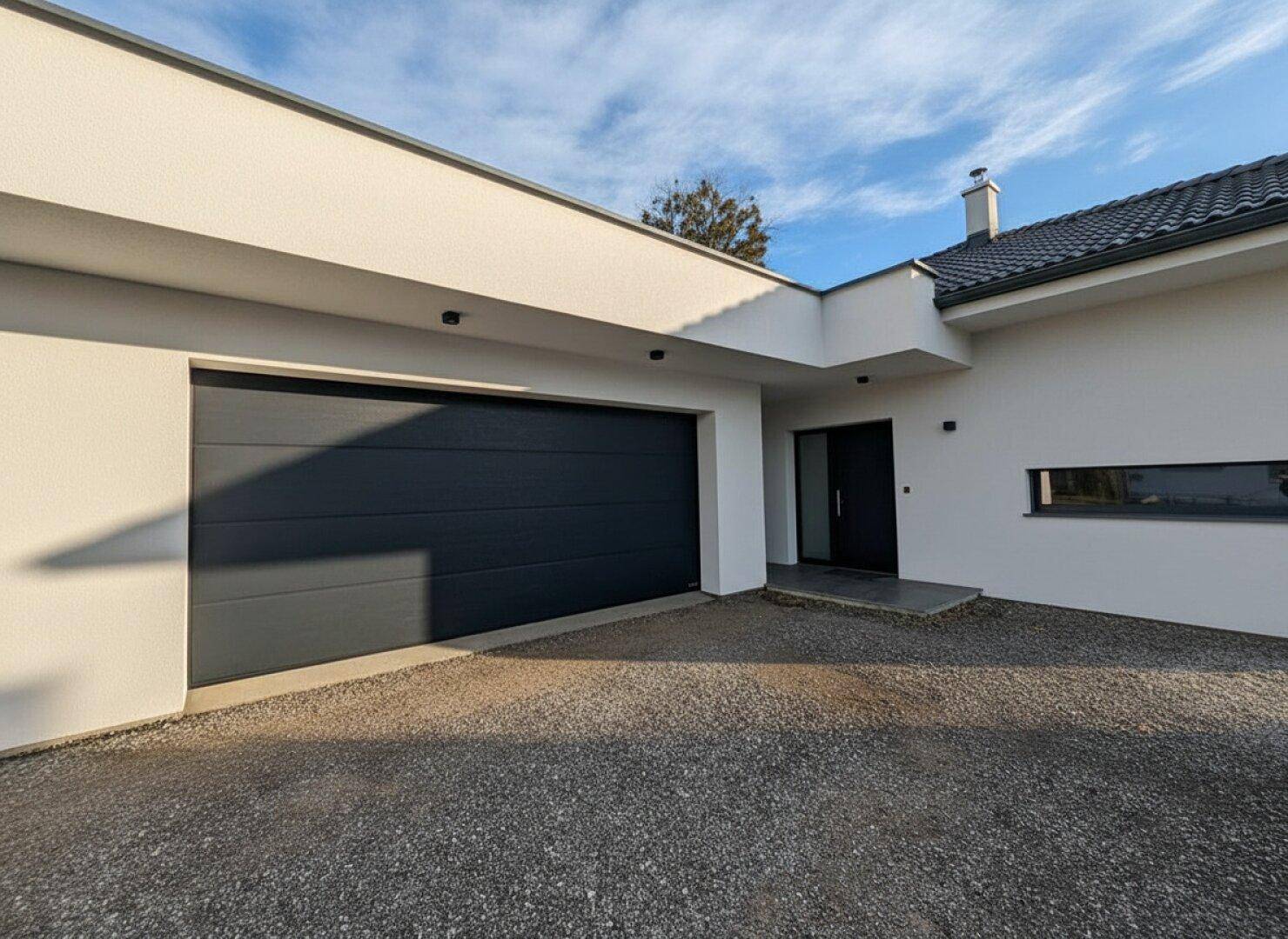 Ansicht des modernen Hauses mit großer Garage und einer breiten Kiesauffahrt.