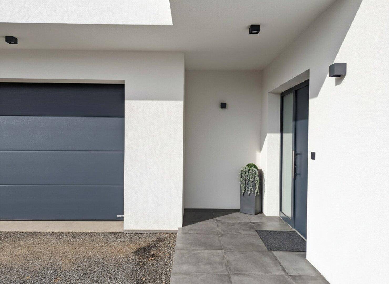 Moderner Eingangsbereich mit Garage und gepflastertem Zugang, der zum Haus führt.