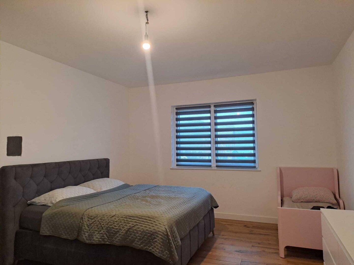Gemütliches Schlafzimmer mit Doppelbett, Kinderbett und Holzboden, ideal für Familien.