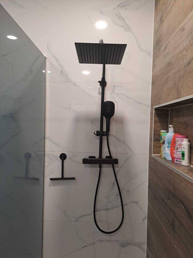 Detailaufnahme der modernen schwarzen Regendusche im stilvollen Badezimmer mit Marmorwand.