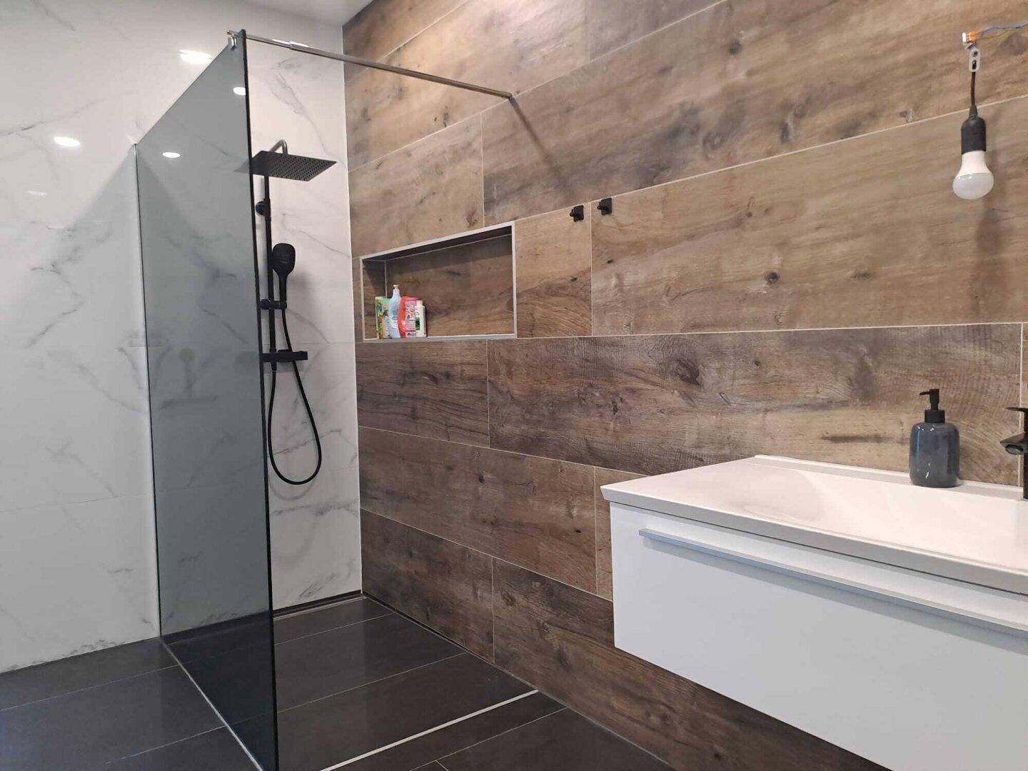 Detailansicht der begehbaren Dusche und des modernen Waschtischs im stilvollen Badezimmer.