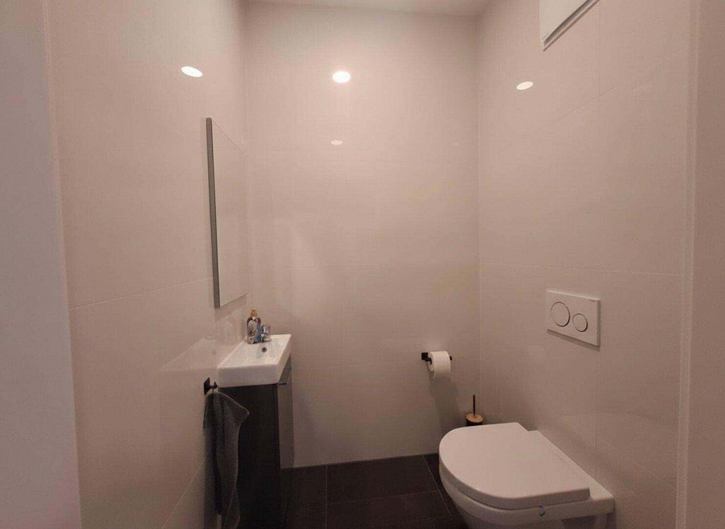 Helles Gäste-WC mit modernem Waschtisch, Wand-WC und dunklem Fliesenboden.