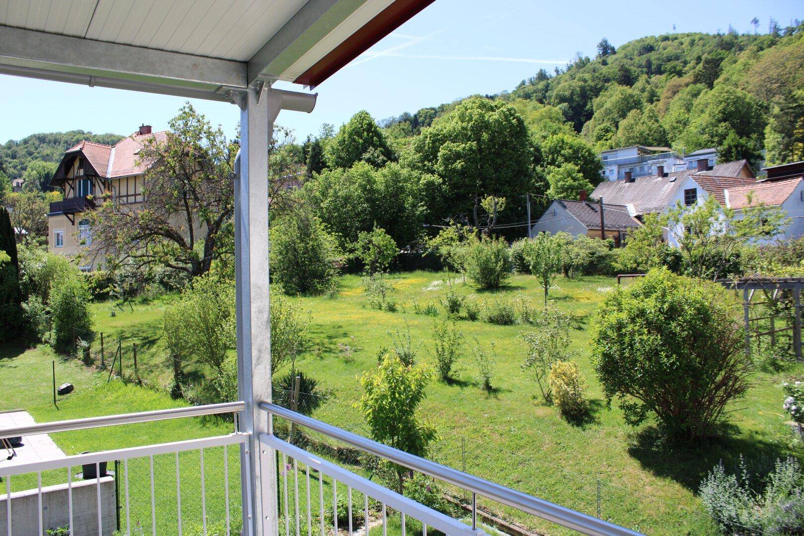 Balkon mit weitem Blick auf die grüne Landschaft und umliegende Häuser.