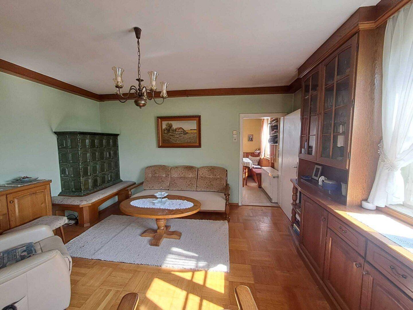 Traditionelles Wohnzimmer mit Kachelofen, Holzparkett und antiken Möbeln.