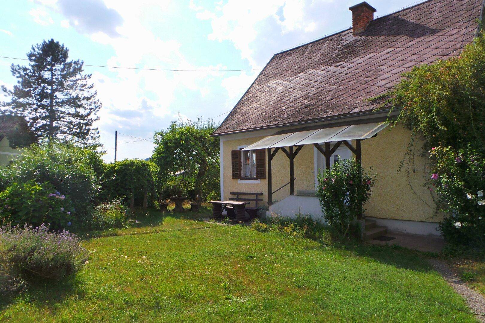 Gelbes Haus mit rotem Dach, überdachtem Eingang und weitläufigem grünen Garten.