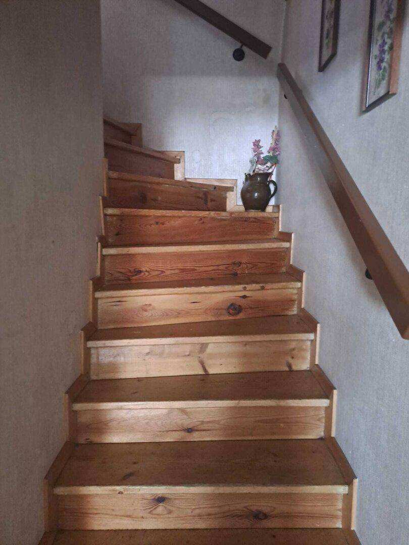 Rustikale Holztreppe mit Geländer, die in die obere Etage führt.