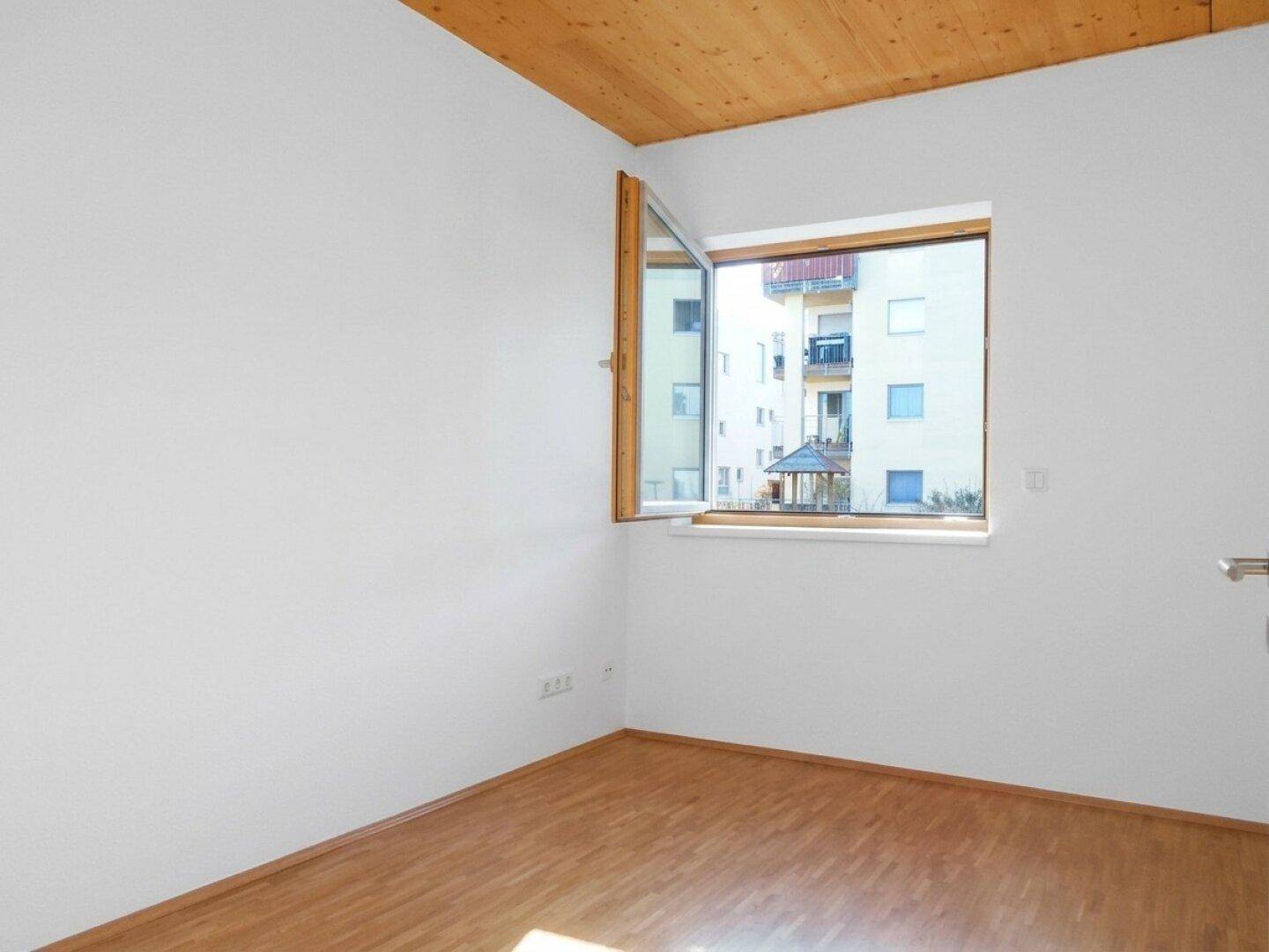 Geräumiges, helles Zimmer mit Holzbalkendecke und Parkettboden, ideal als Schlaf- oder Arbeitszimmer.
