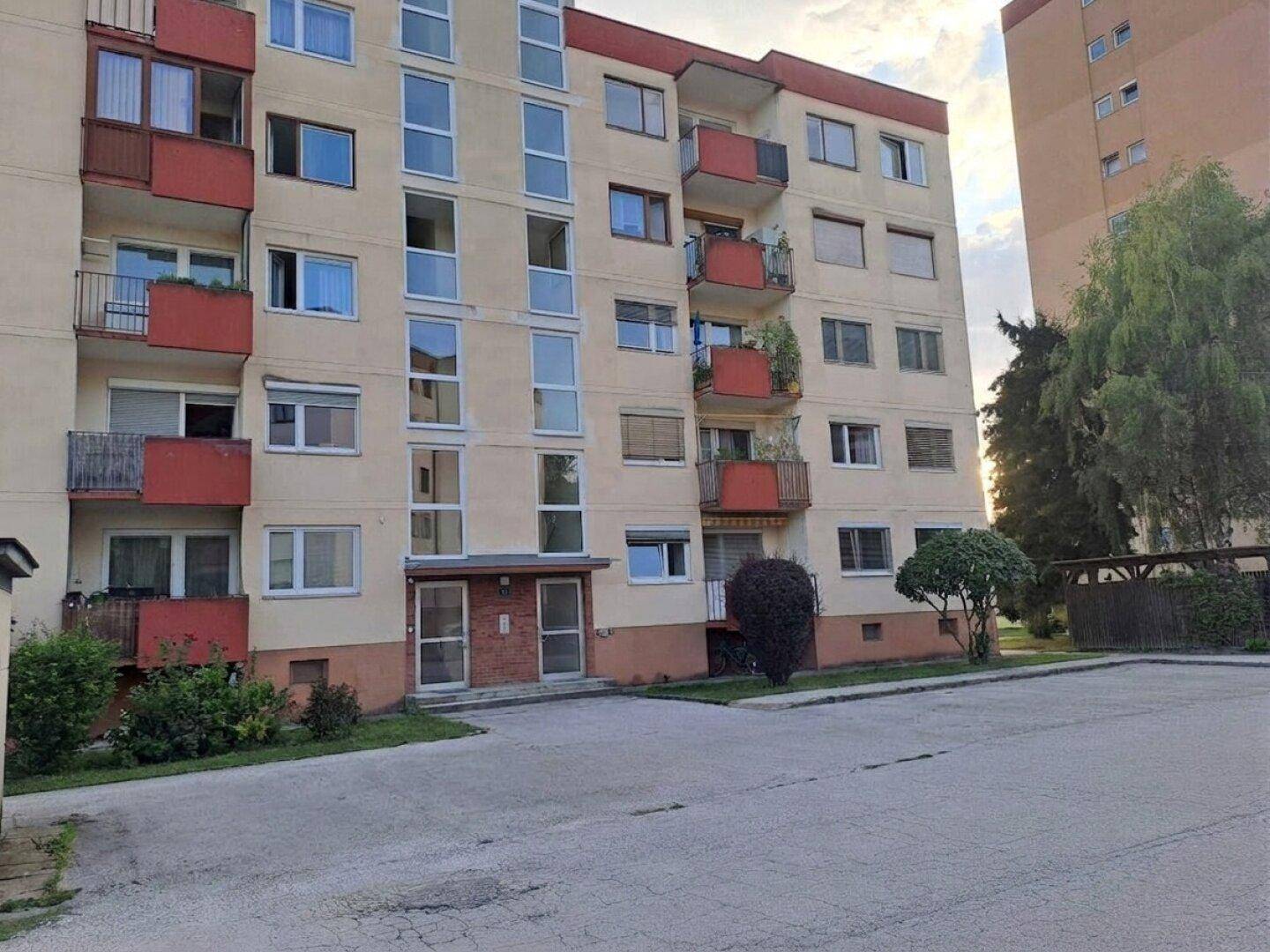 Ansicht der Gebäudefassade eines Mehrfamilienhauses mit mehreren Balkonen und Eingangsbereichen.