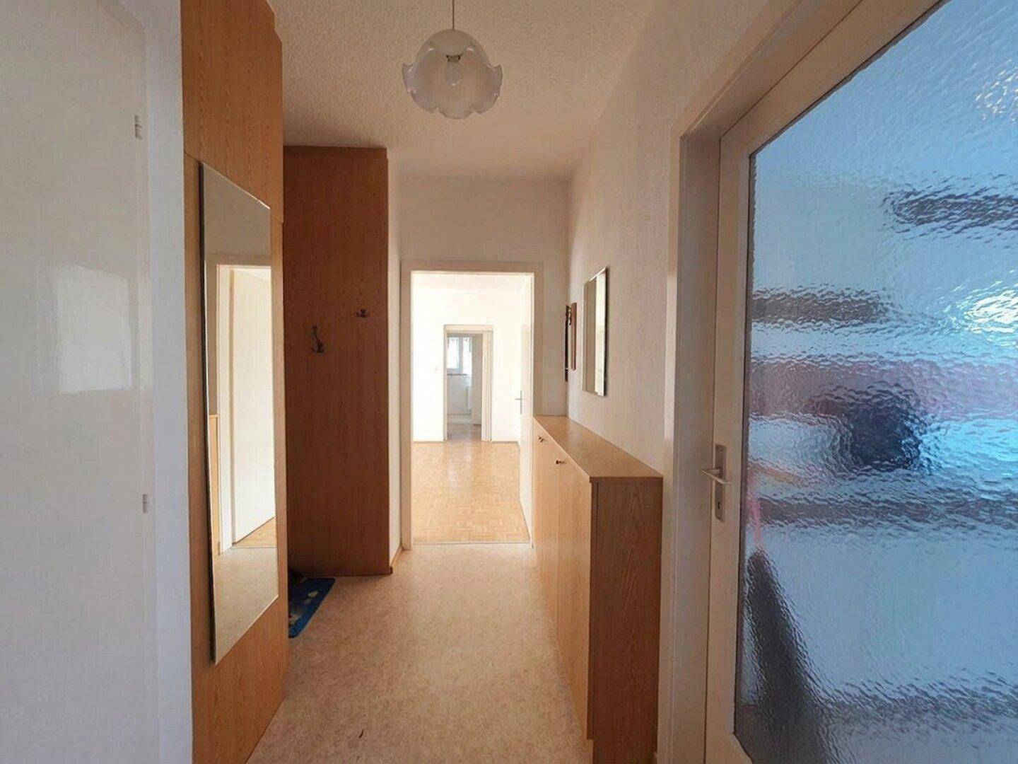 Geräumiger Flur mit Holzschränken und einem Spiegel, der zu den verschiedenen Zimmern führt.