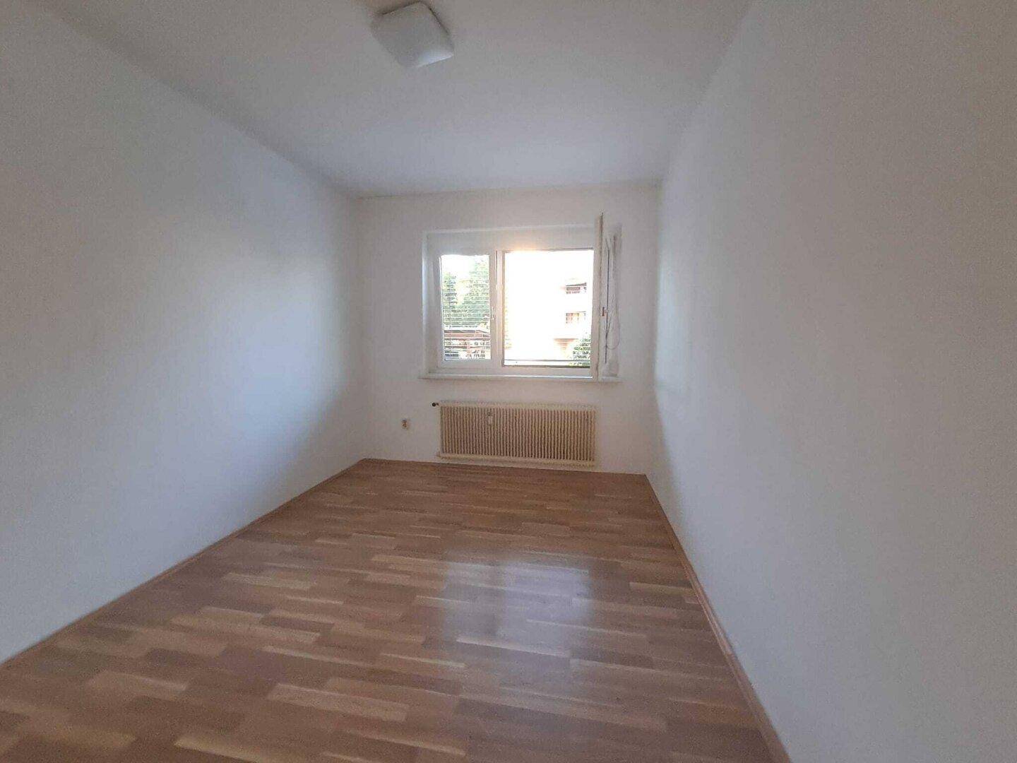 Ruhiges Schlafzimmer mit Parkettboden und einem Fenster, das für eine angenehme Belichtung sorgt.