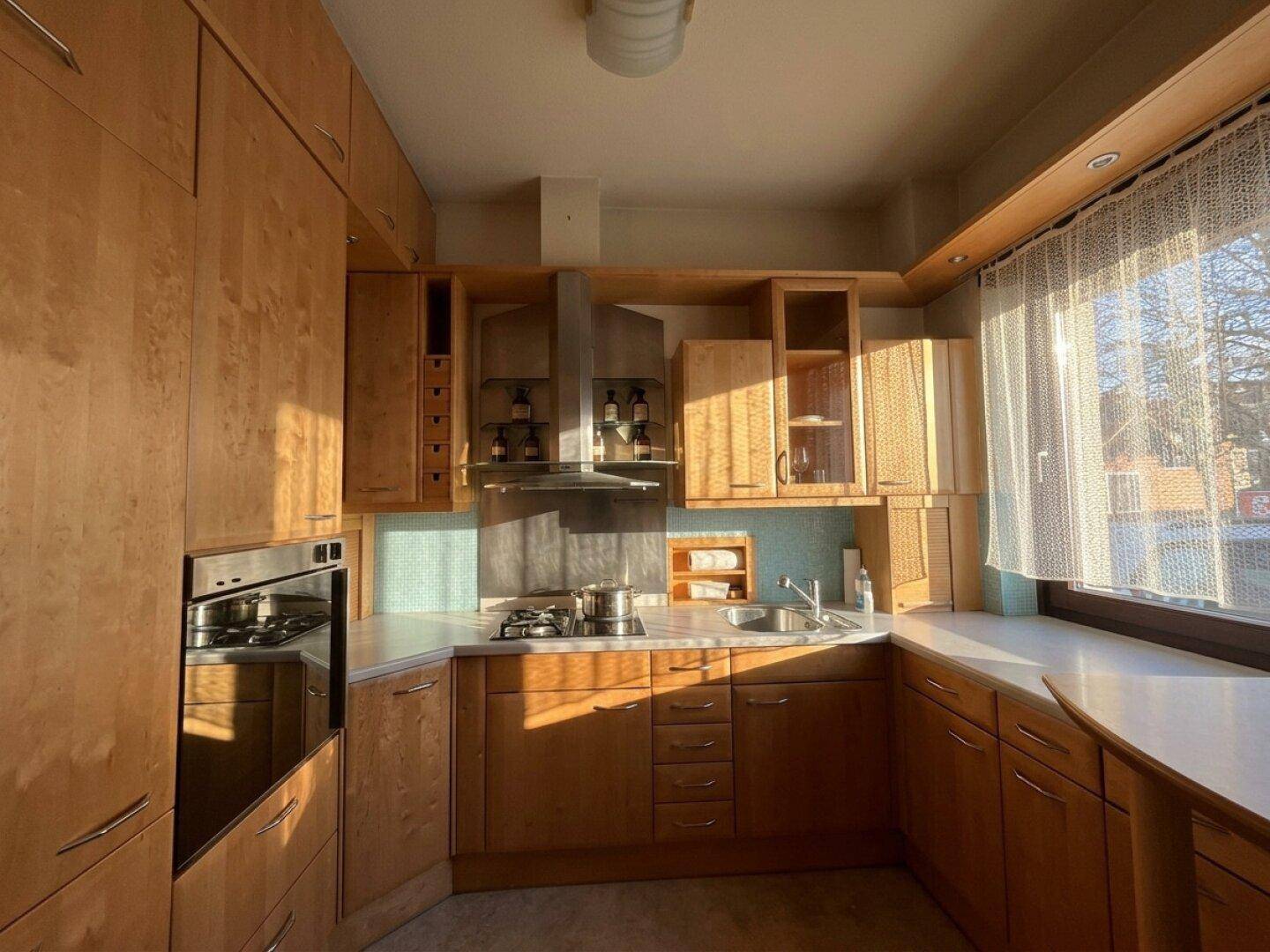 Helle Holzküche mit modernen Geräten und viel Stauraum, durchflutet von Sonnenlicht.
