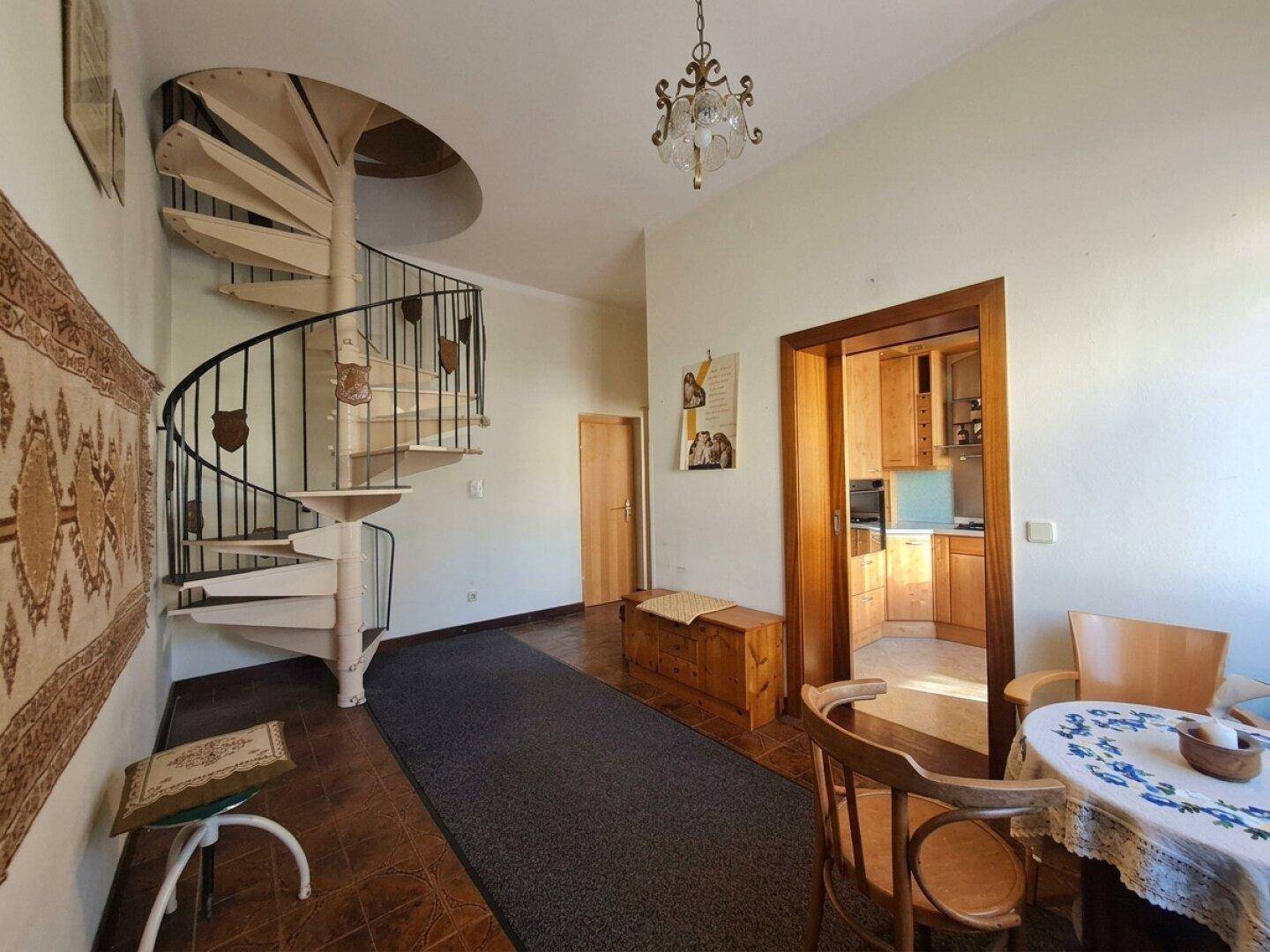 Heller Flur mit einer eleganten Wendeltreppe und Blick in einen angrenzenden Wohnbereich.