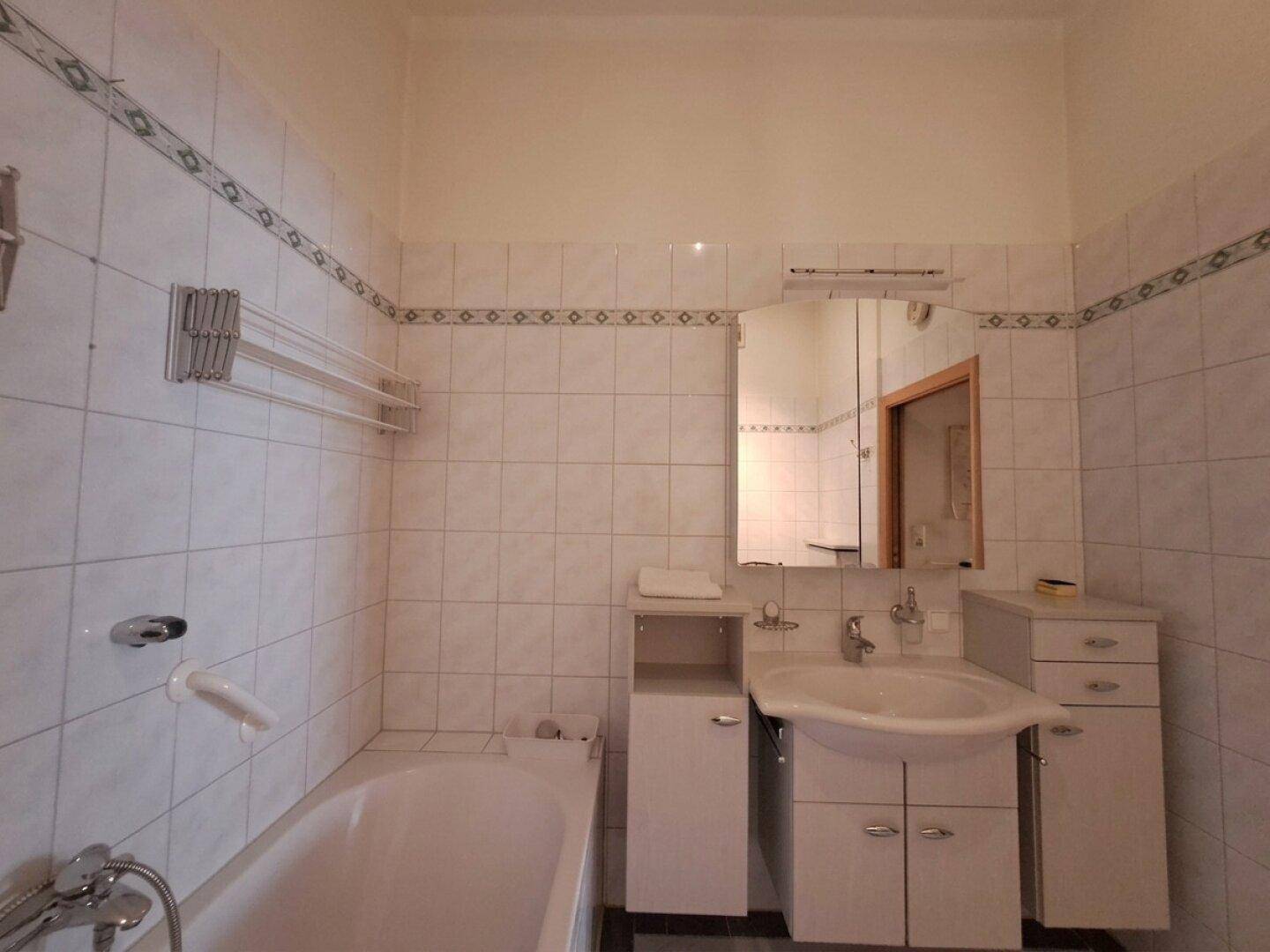 Klassisches Badezimmer mit Badewanne, Waschtisch und Fliesen im traditionellen Stil.