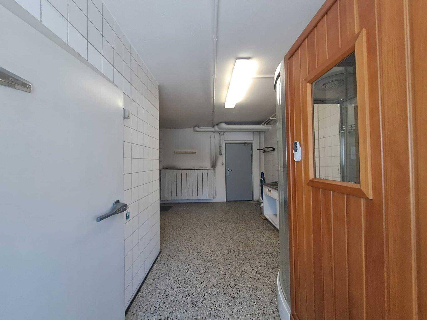 Funktionaler Hauswirtschaftsraum mit Fliesenwänden und Zugang zu einer Sauna.
