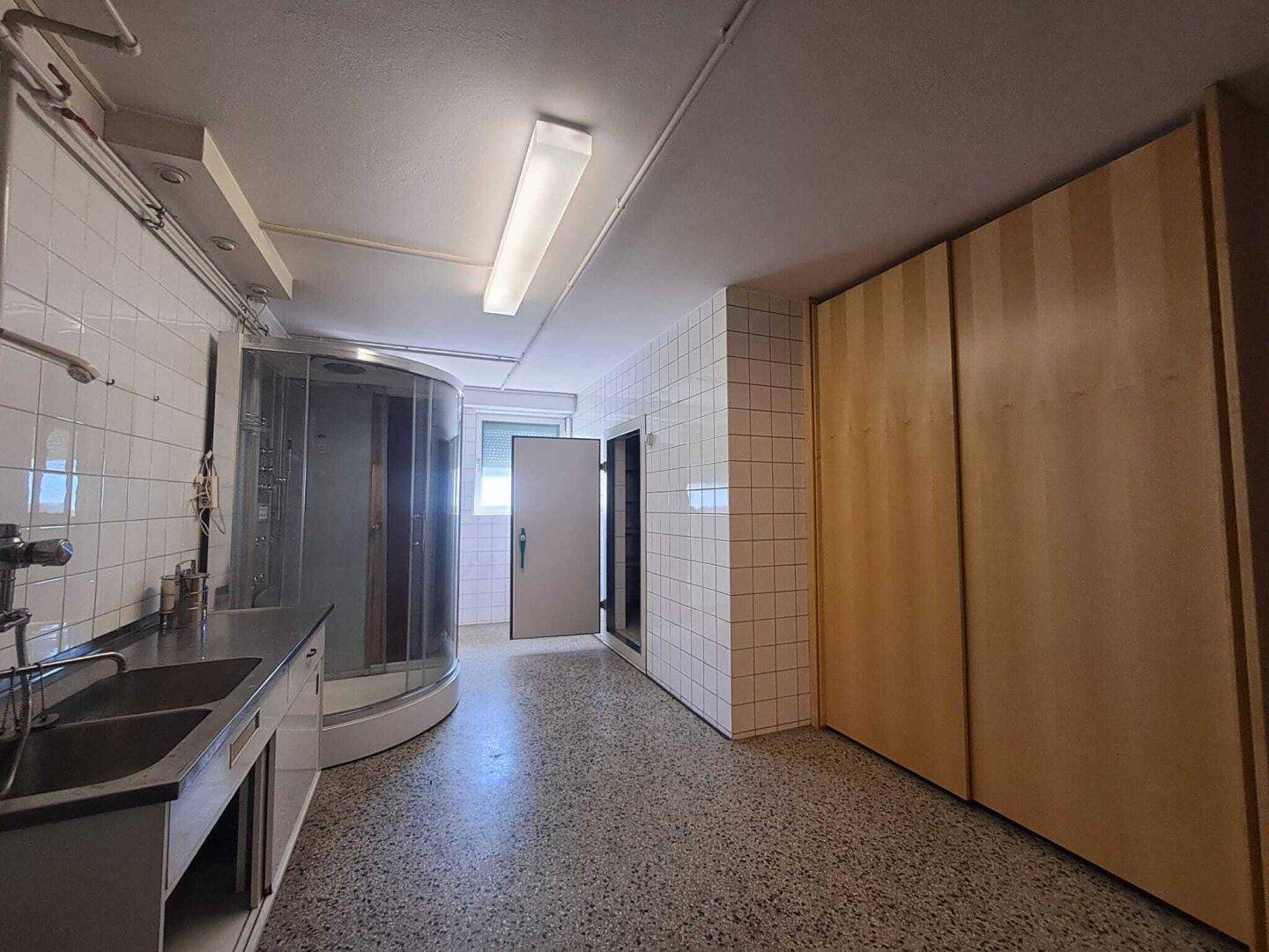Funktionaler Badezimmerbereich mit Duschkabine, Doppelwaschbecken und integrierten Holzschränken.