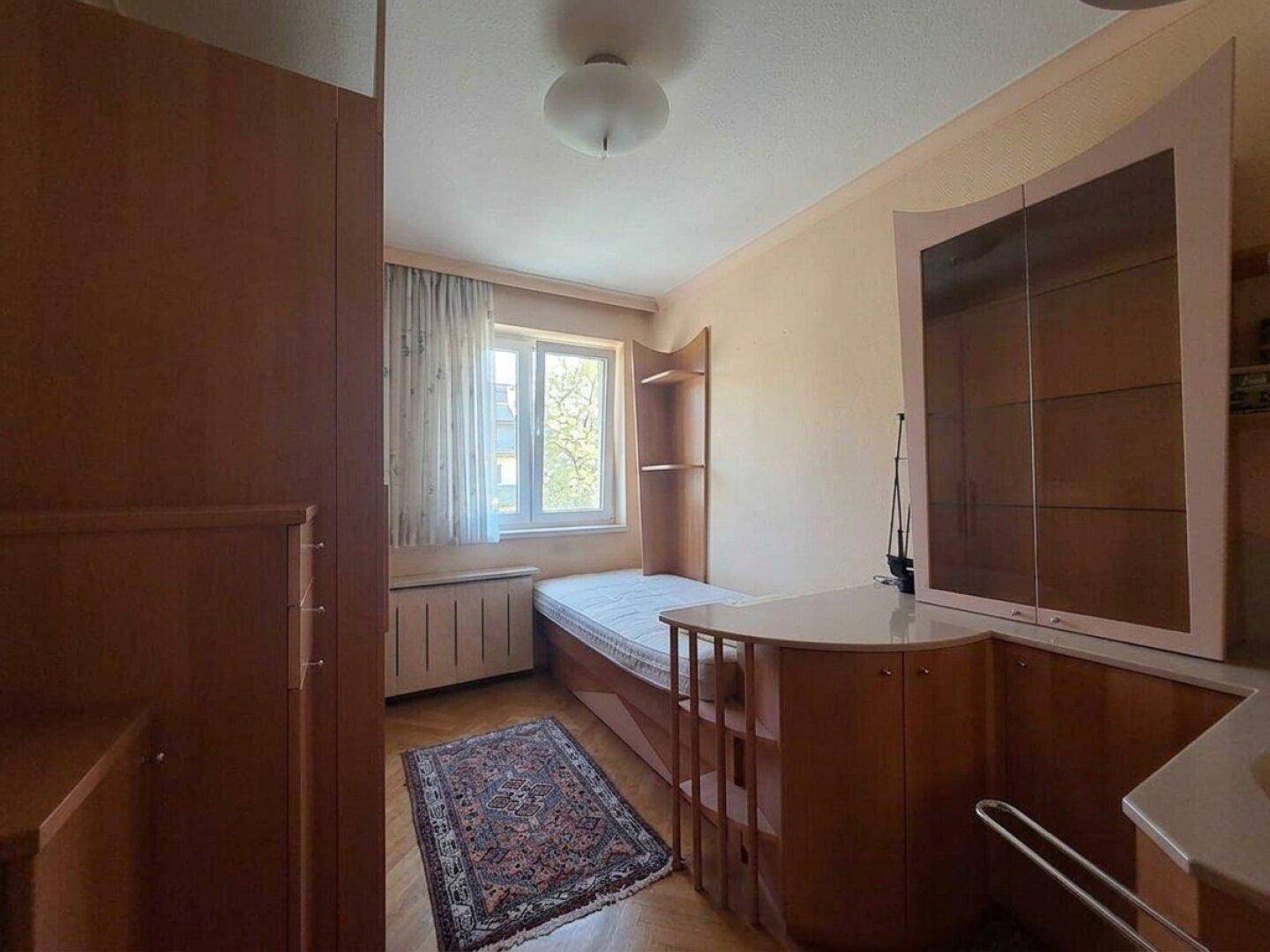 Schlafzimmer mit Parkettboden, Einbauschränken und Fenster, das viel Tageslicht hereinlässt.
