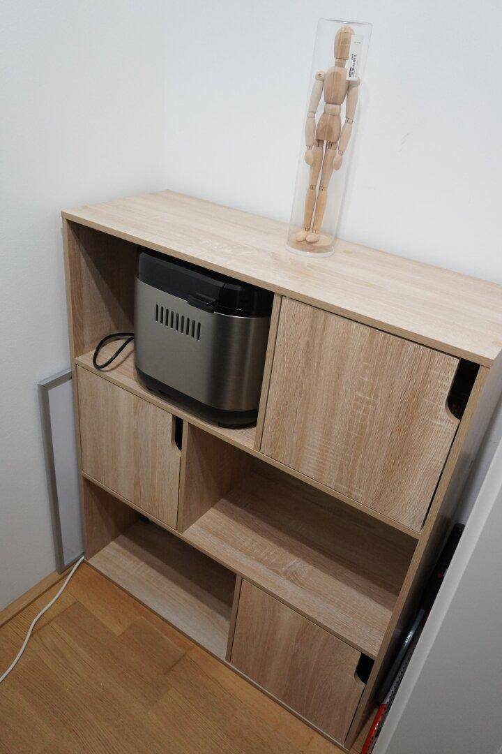 Praktisches Regal mit Holzoptik und integriertem Brotautomaten, auf hellem Holzboden.