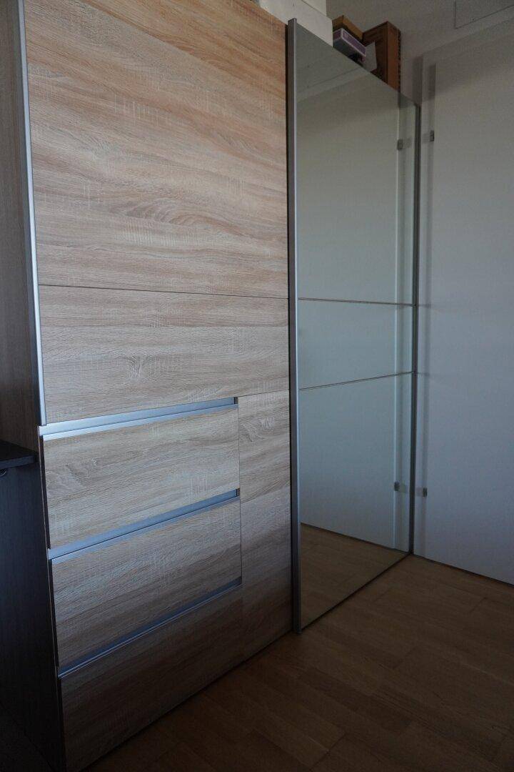 Geräumiger Kleiderschrank mit Holzfronten und Spiegeltüren, auf hellem Holzboden.