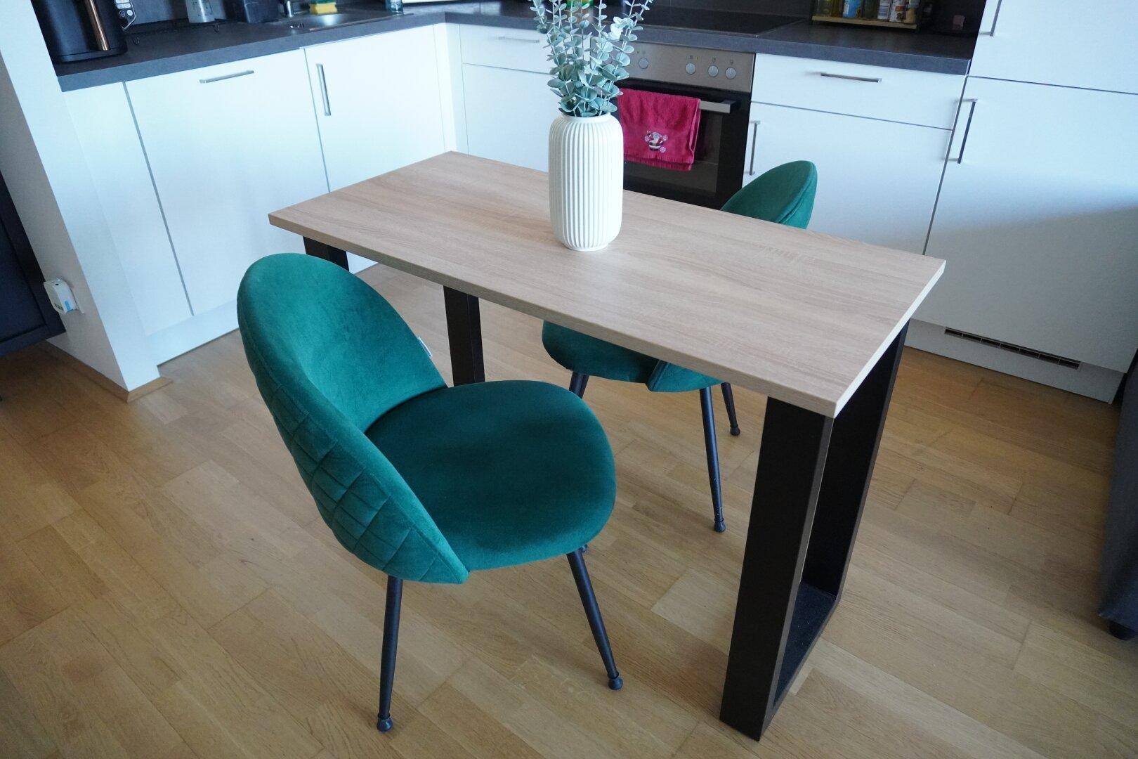 Moderne Küche mit Holzboden und kleinem Esstisch, perfekt für Mahlzeiten zu zweit.