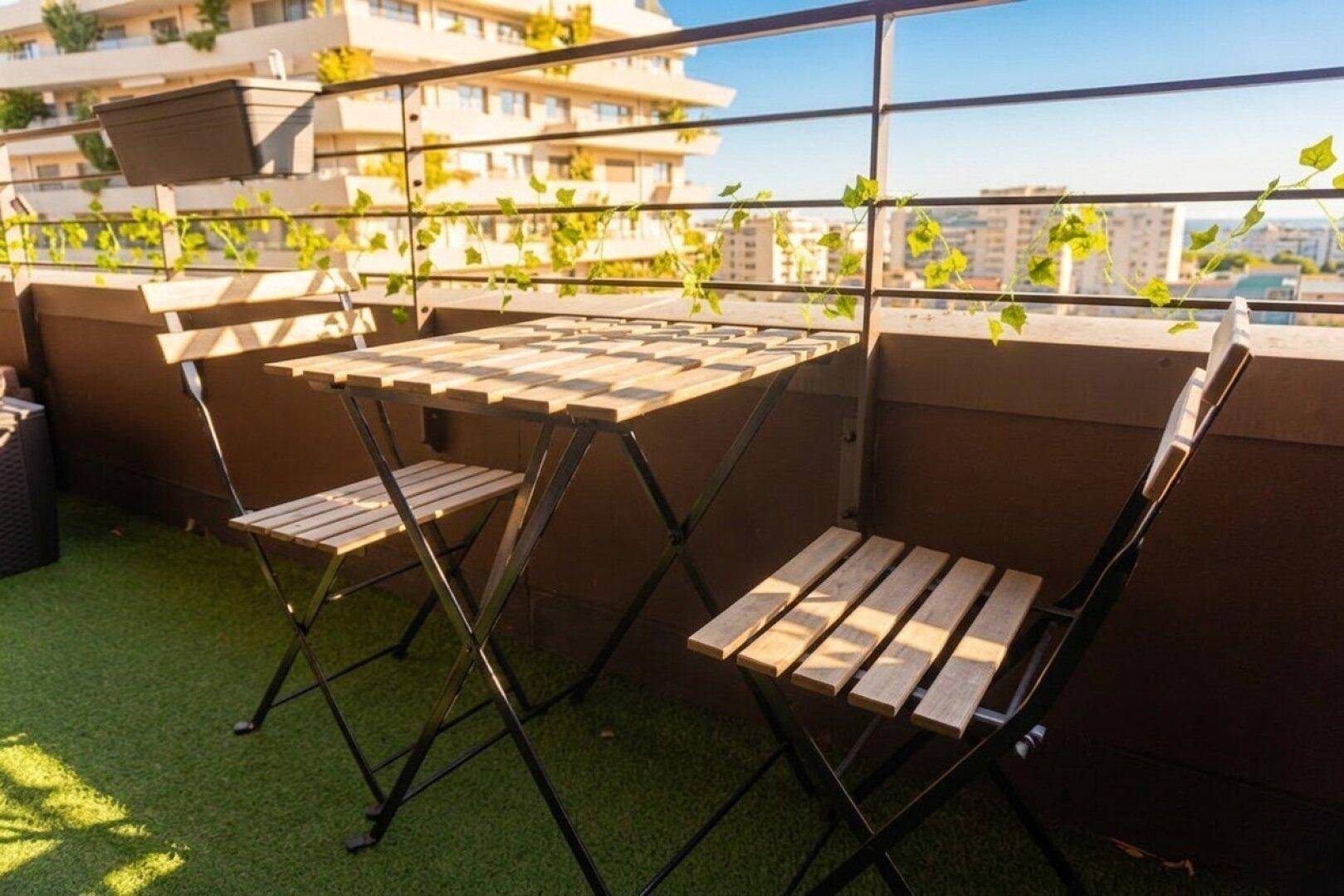 Heller Balkon mit Klapptisch und Stühlen, bietet einen schönen Blick auf die Umgebung.