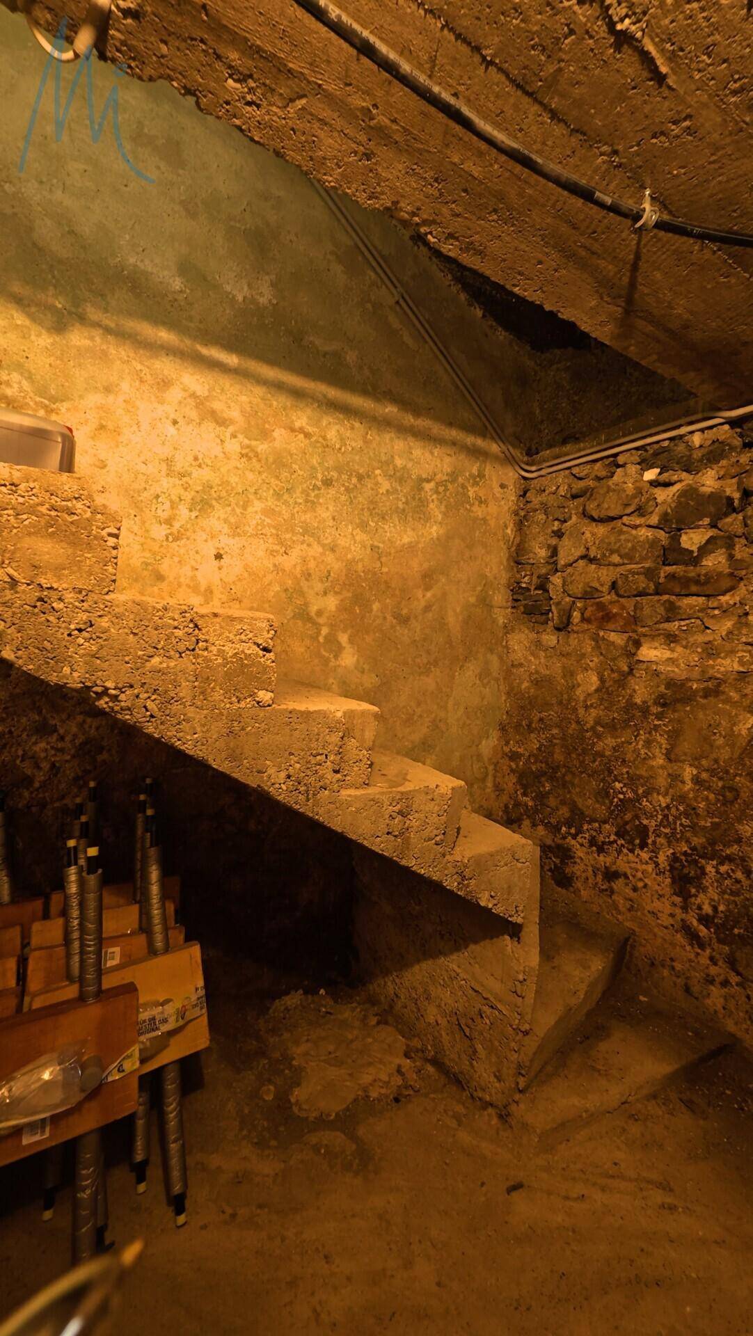 Rustikaler Kellerraum mit Steintreppe und unverputzten Wänden.