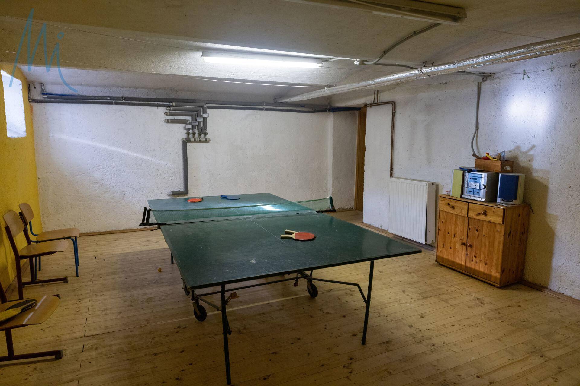 Spielzimmer im Keller mit Tischtennisplatte und Holzboden, ideal für Freizeitaktivitäten.