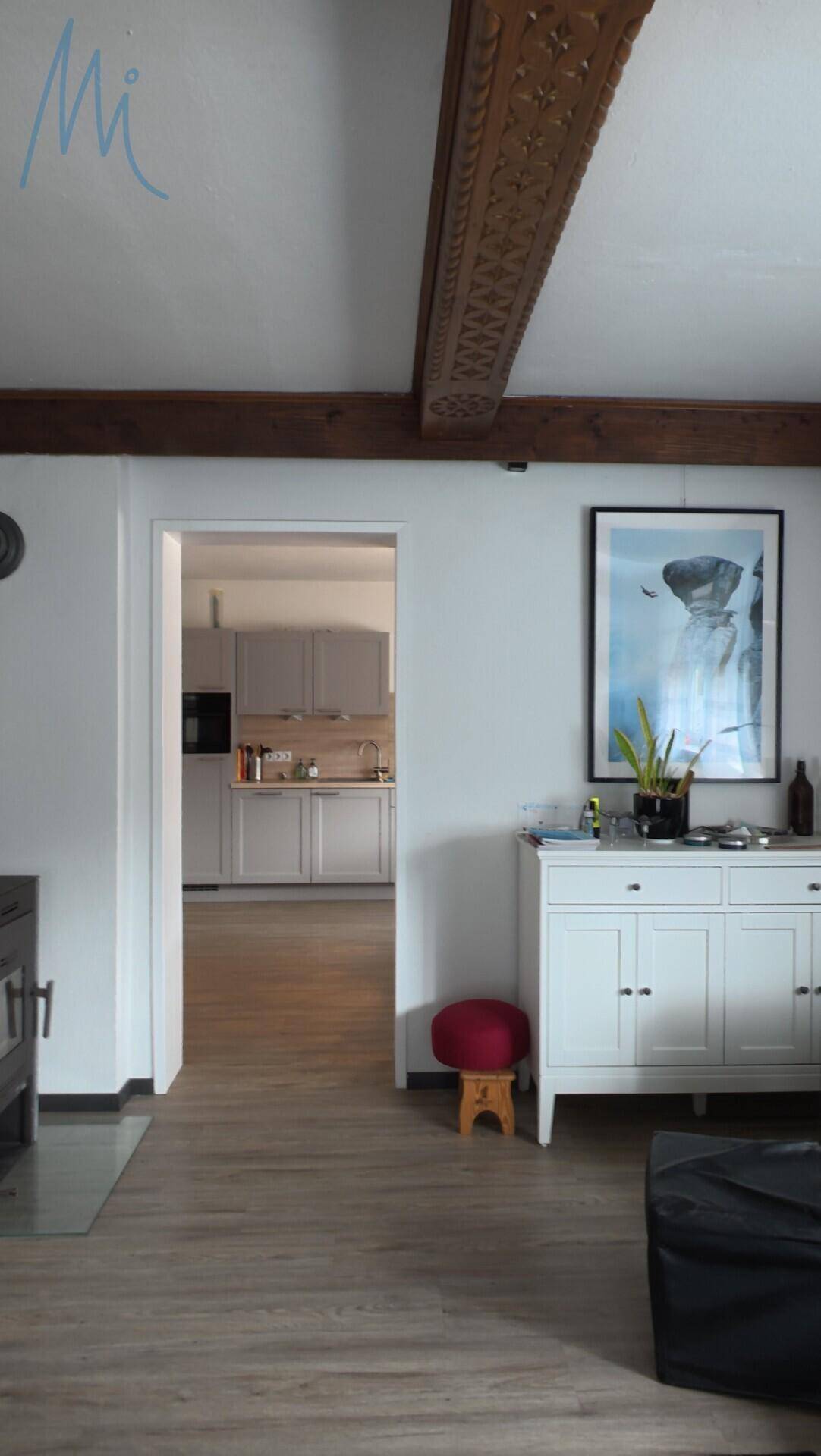 Durchgang vom Wohnzimmer zur modernen Küche mit Holzbalkendecke.