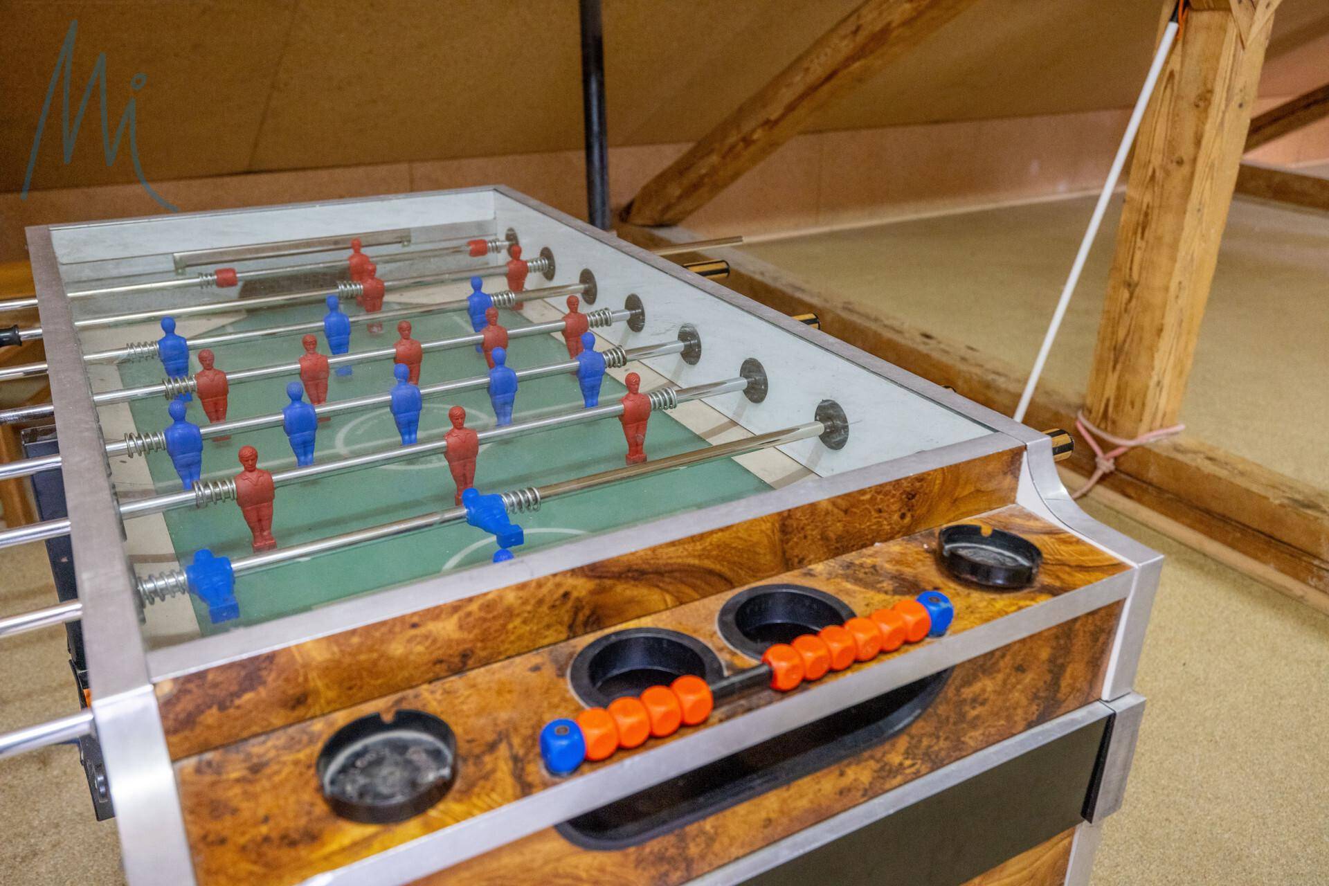 Spielzimmer im Dachgeschoss mit einem Tischfußballspiel und sichtbaren Holzbalken, ideal für Freizeitaktivitäten.