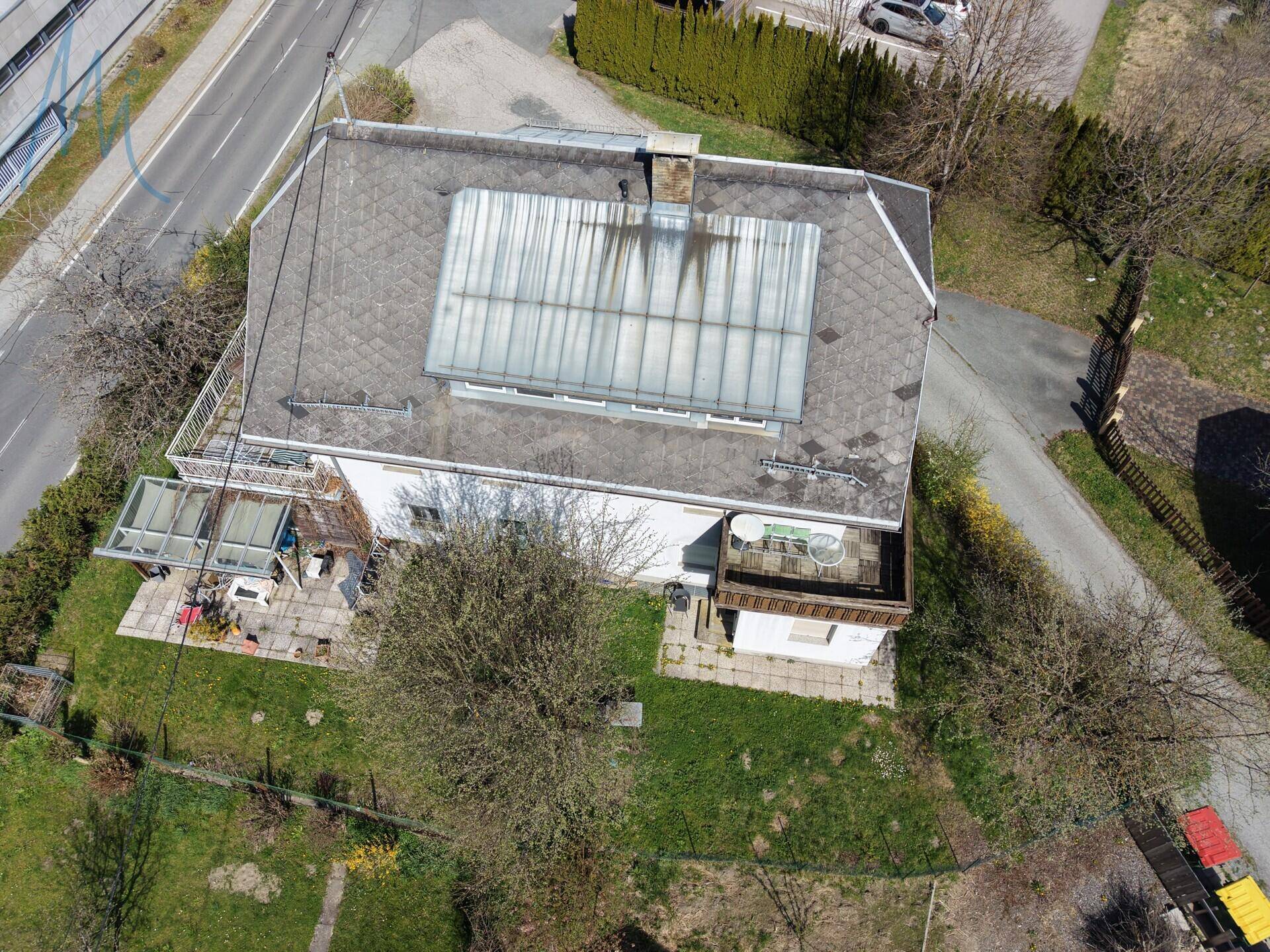 Draufsicht auf das Wohnhaus mit großem Satteldach, Terrassenbereichen und einem gepflegten Garten.