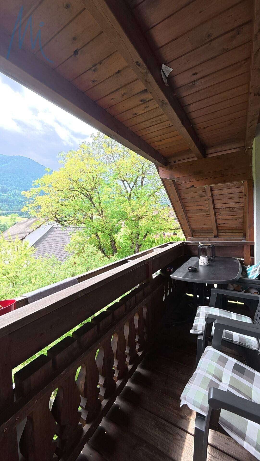 Gemütlicher Balkon mit Holzboden und atemberaubendem Blick auf die umliegenden Berge.