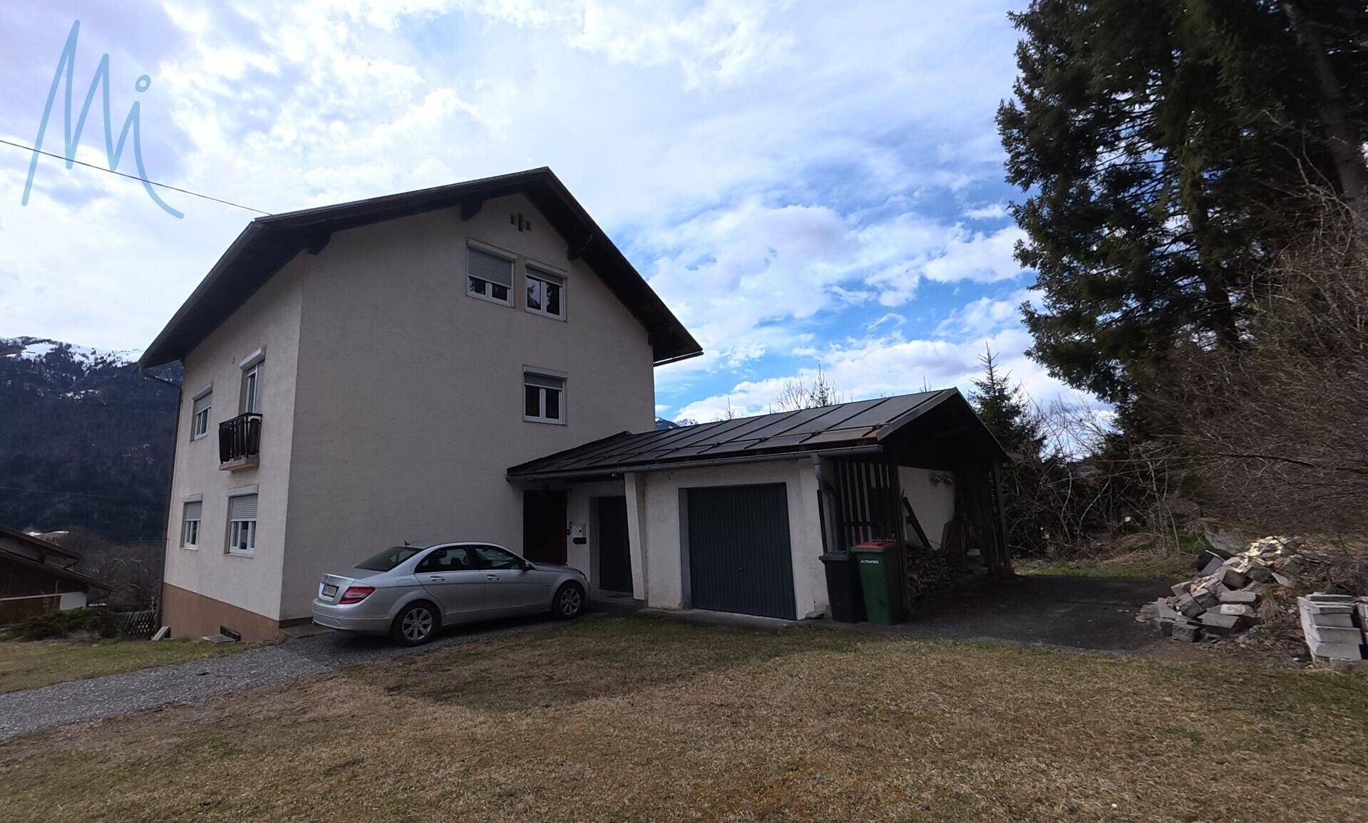 Wohnhaus mit angeschlossener Garage und Stellplatz im Freien.