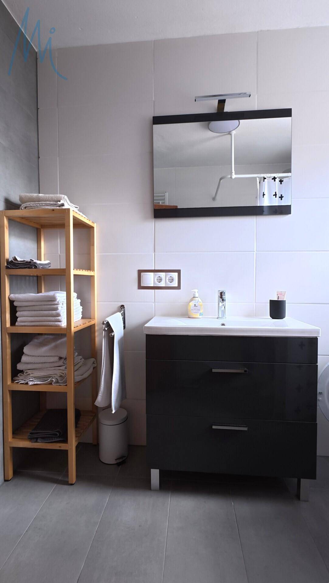 Modernes Badezimmer mit Waschbecken, Spiegel und Holzregal.